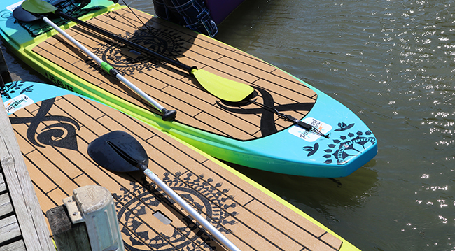 Two brightly colored paddle boards next to a dock on a lake