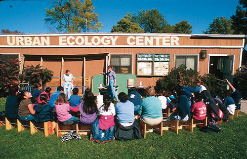 Students sitting outside our original Urban Ecology Center building -- a double wide trailer